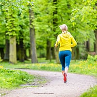 Woman runner running with dog in park summer nature exercising in bright forest outdoors